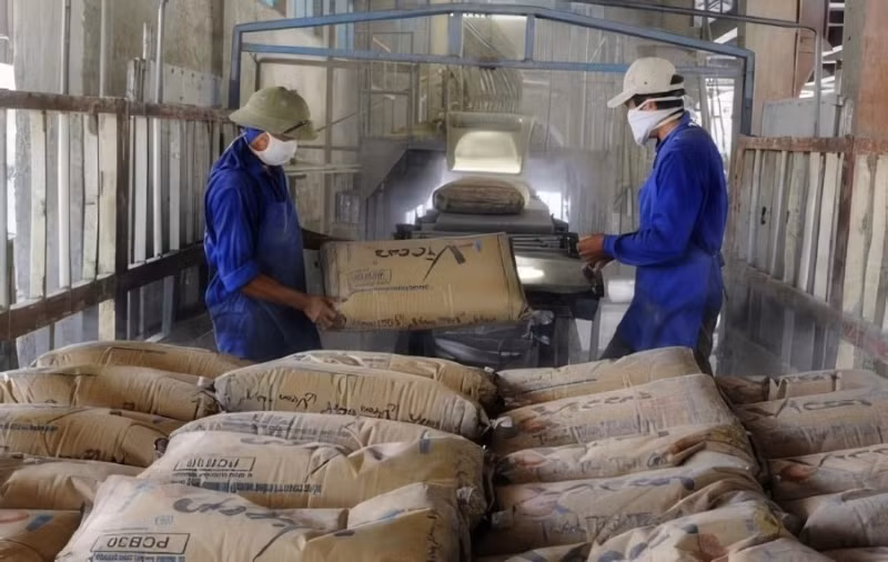 Des ouvrier transportent des sacs de ciment dans une usine. Photo : Vicem.
