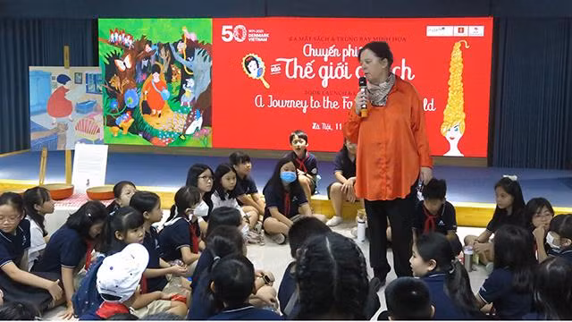 L’artiste danoise Tove K. Lange échange avec des enfants vietnamiens. Photo : Linh Vi/NDEL.