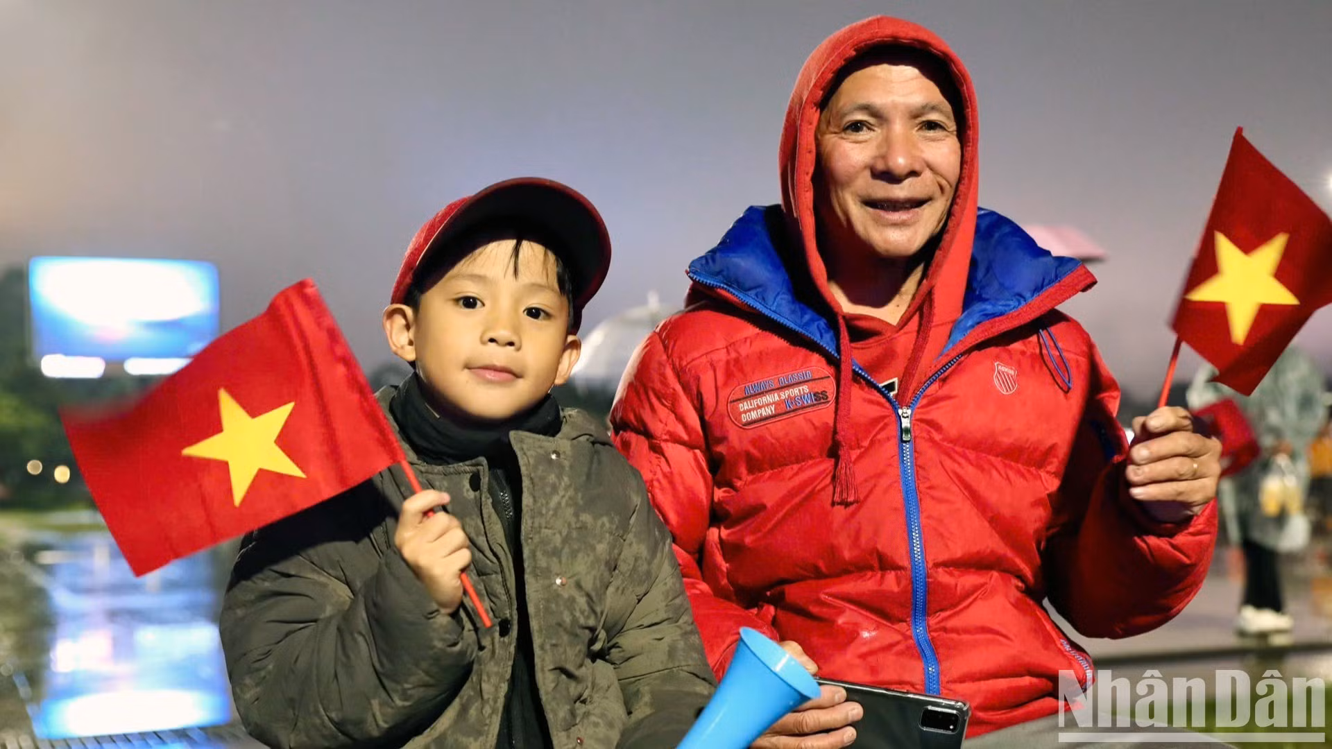 Deux générations d’une même famille affrontent la pluie et le froid pour célébrer ensemble la victoire de l’équipe nationale. (Photo : Mai Van Bao)