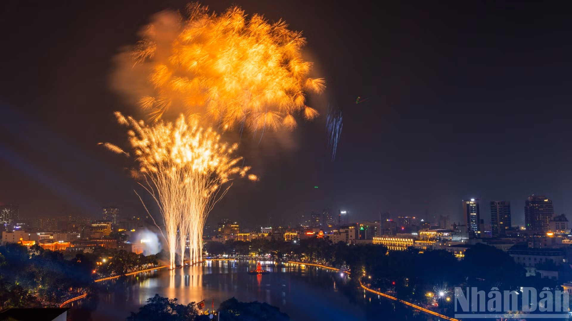 Au cœur de Hanoï, le lac Hoan Kiem se pare de reflets multicolores. Les gerbes des feux d’artifice se mêlent aux lumières des rues environnantes pour composer un paysage scintillant.