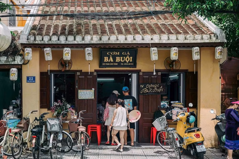 Des touristes se rendent au restaurant Com ga Ba Buoi, rue Phan Chu Trinh, une adresse réputée pour découvrir le riz au poulet de Hoi An.