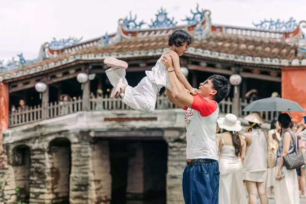 Un père et son enfant partagent un moment de complicité devant le pont-pagode.