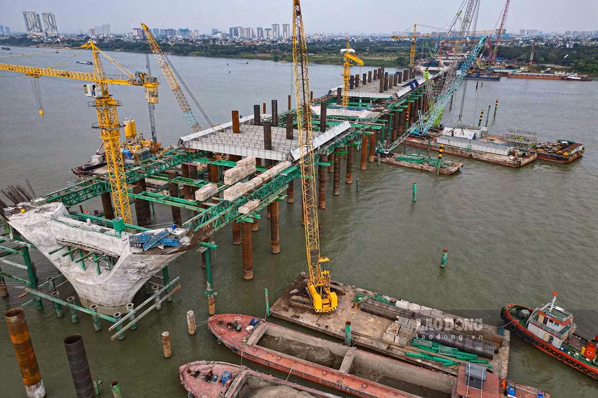 Le chantier entre dans une phase décisive de réalisation des structures porteuses. Plusieurs piles s’élèvent désormais au milieu du fleuve Rouge, tandis que des éléments de charpente métallique sont progressivement mis en place.