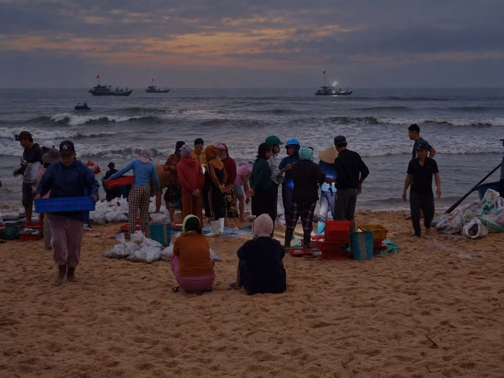 Les bateaux rentrent après une nuit de pêche. Sur la plage, les commerçants attendent déjà, alignés face au large. Photo : VHO.