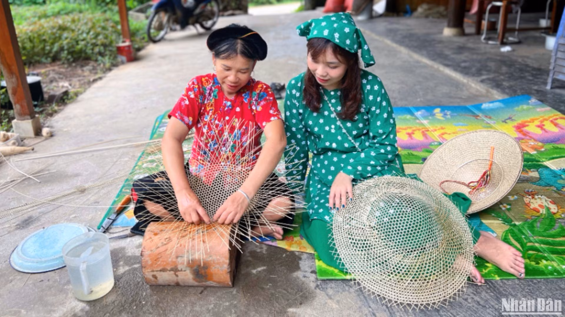 Madame Hoang Thi Hue (à gauche) échange avec des visiteurs et leur montre comment confectionner un chapeau.