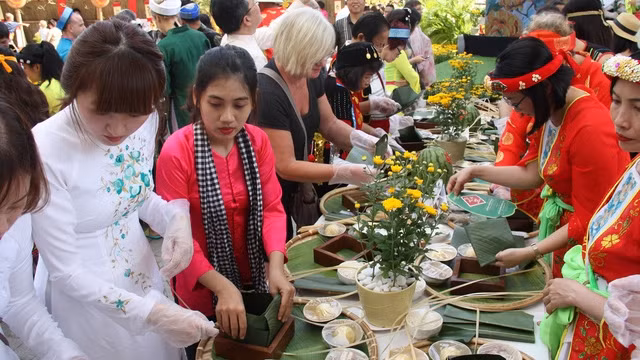 Des touristes étrangers font l’expérience du Têt vietnamien avec le festival du " Banh Chung ". Photo : TQ
