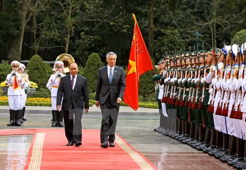 Le PM vietnamien Nguyên Xuân Phuc (à gauche) et son homologue singapourien Lee Hsien Loong inspectent la garde d’honneur lors de la cérémonie de bienvenue à Hanoi. Photo: VNA.