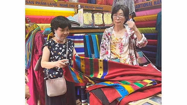 Une visiteuse achète des produits au village de la soie de Van Phuc. Photo : kinhtedothi.vn