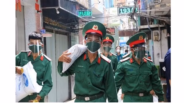 Soldats portant des sacs de riz pour faire don aux démunis de Hô Chi Minh-Ville, le 23 août. Photo : VNA.