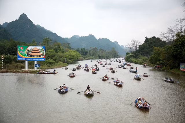 Les visiteurs prennent de petits bateaux le long des voies navigables serpentant entre les falaises de calcaire pour accéder à la pagode des Parfums. Photo : kinhtedothi.vn.